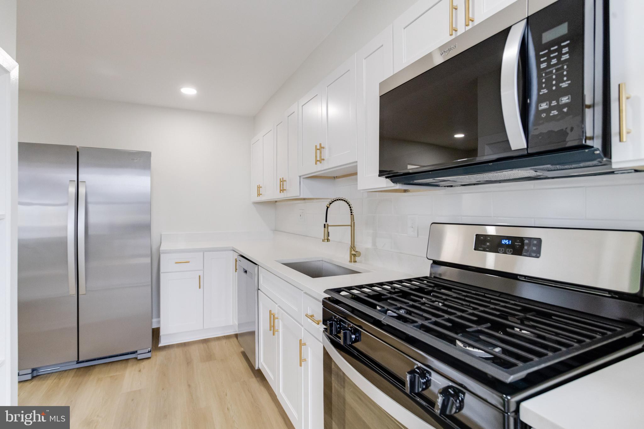 3916 2nd Street Baltimore, MD 21225 - Photo 6 of 20 a kitchen with stainless steel appliances granite countertop a stove a microwave and a sink