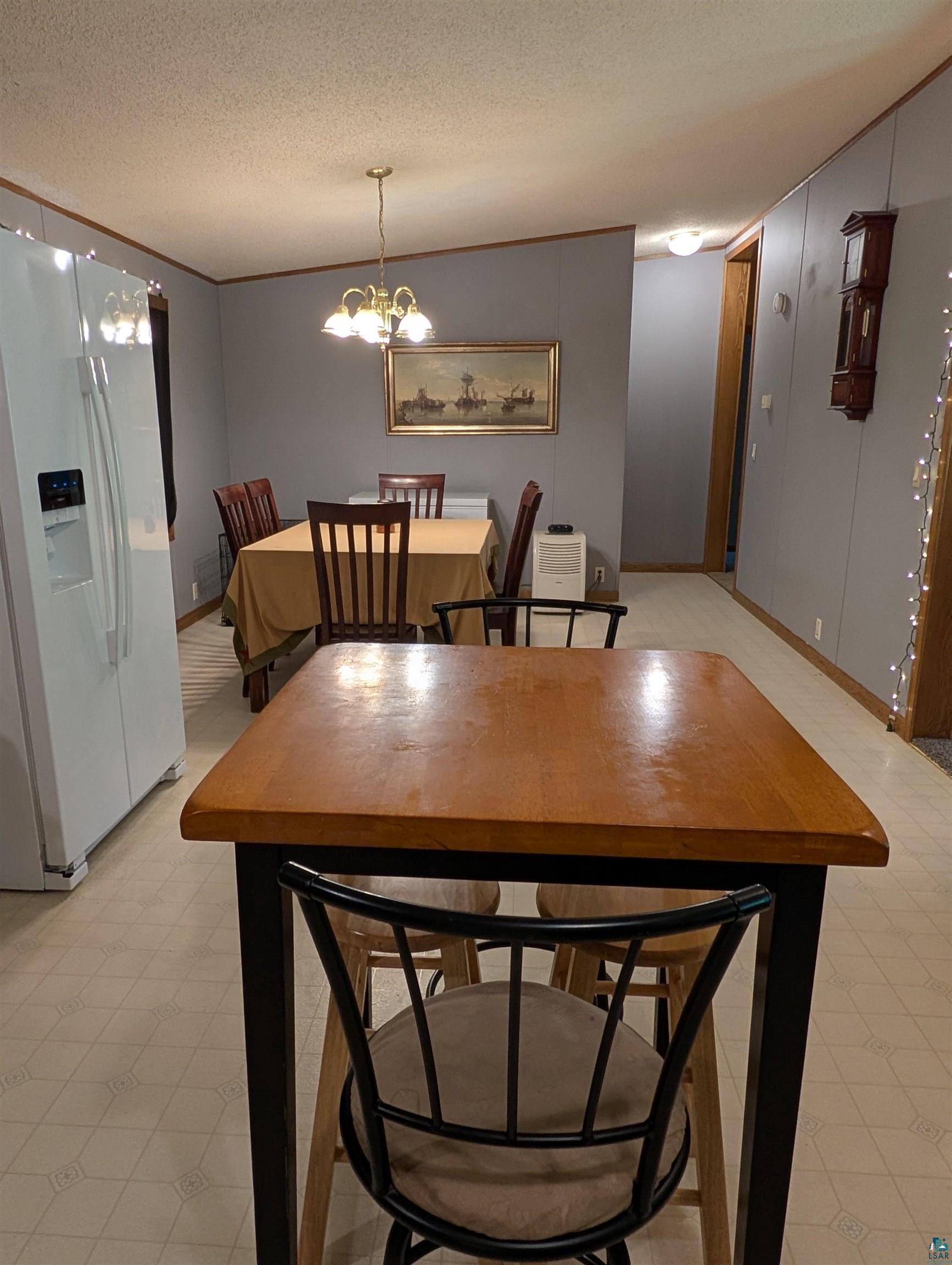 3945 Maple Street Kettle River, MN 55757 - Photo 3 of 41 Open-concept dining area featuring a chandelier, a breakfast bar with a wood-finish top, and paneled walls
