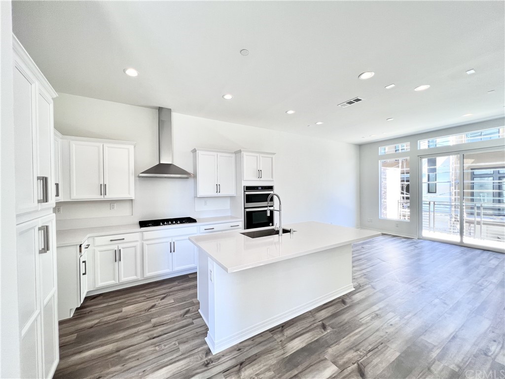126 Sawbuck Irvine, CA 92618 - Photo 2 of 10 a large kitchen with stainless steel appliances a large counter top a stove a refrigerator with white cabinets and wooden floor