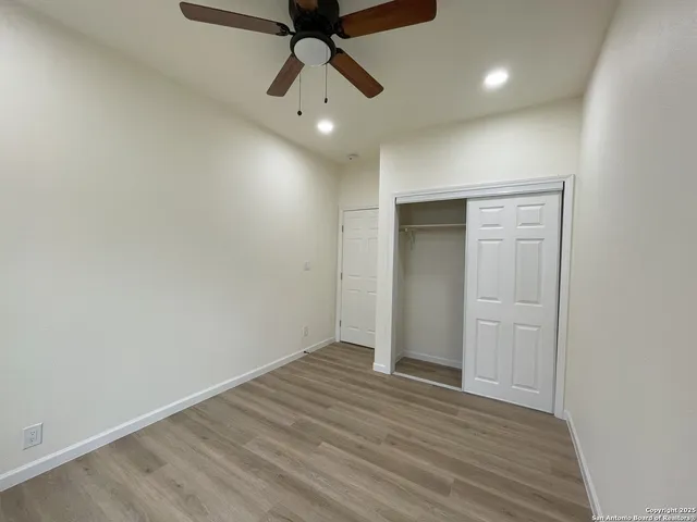 an empty room with wooden floor and ceiling fan