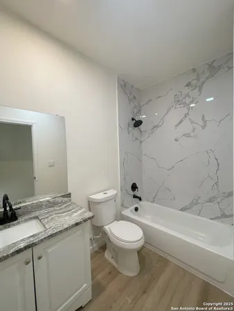 a bathroom with a granite countertop sink a toilet and shower