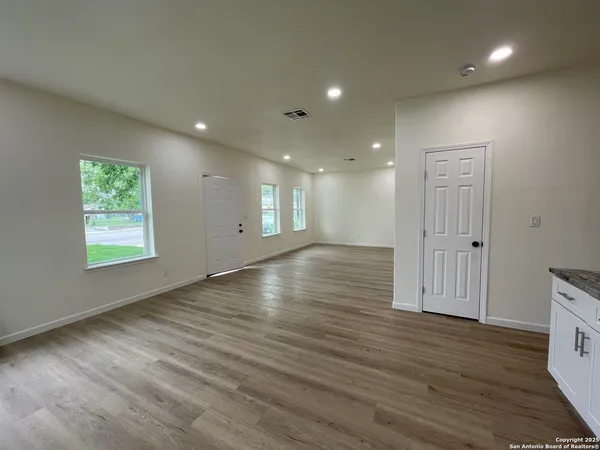 an empty room with wooden floor and windows
