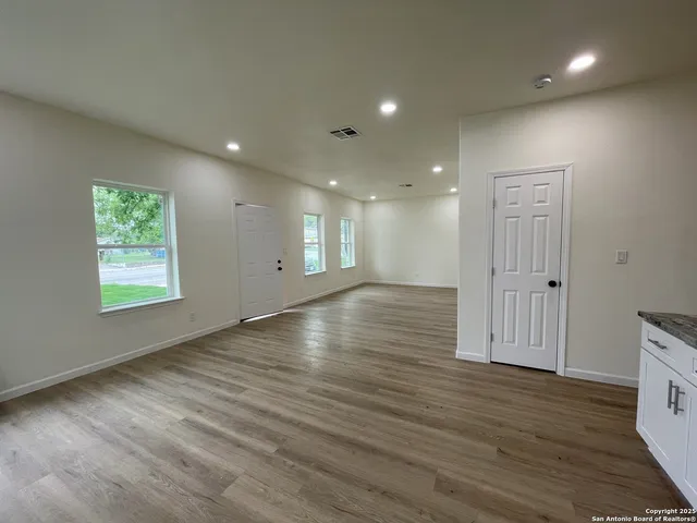 an empty room with wooden floor and windows
