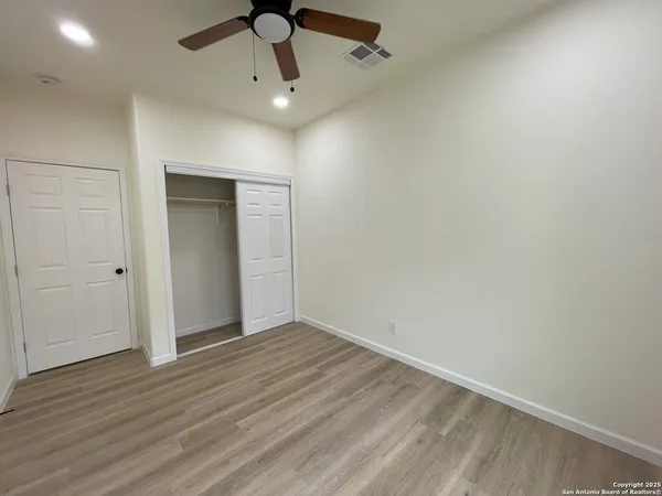 an empty room with wooden floor ceiling fan and windows