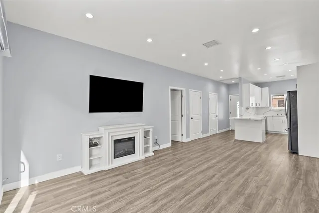 a view of a livingroom with a flat screen tv wooden floor and kitchen