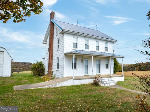 a view of a white house with a big yard and large trees
