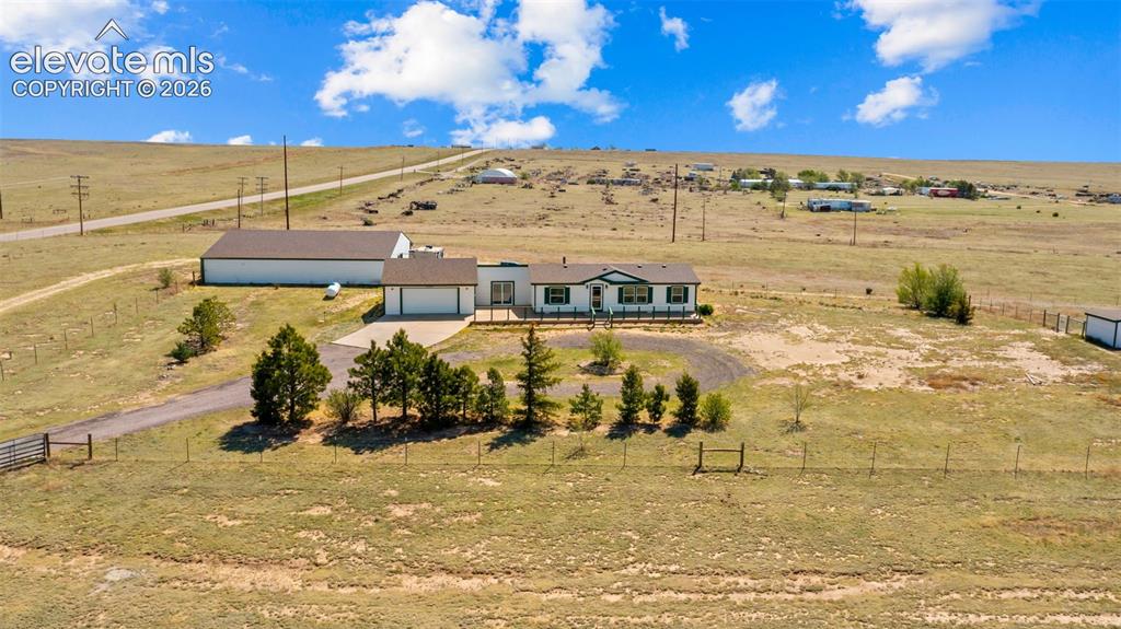 33975 Highway 94 Yoder, CO 80864 - Photo 29 of 40 Expansive property featuring a single-story residence with a two-car garage, a large detached outbuilding, a circular driveway, and mature landscaping