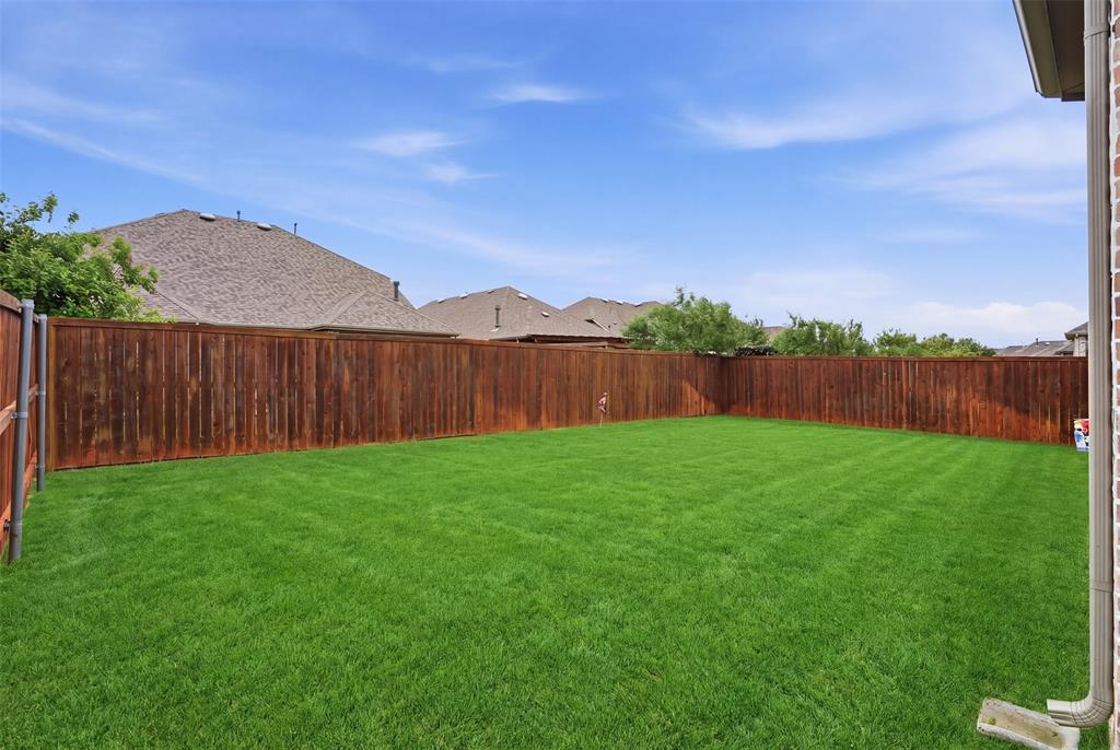 1429 Eclipse Road Aubrey, TX 76227 - Photo 27 of 37 The property features a spacious backyard with a well-maintained lawn, enclosed by a wooden privacy fence