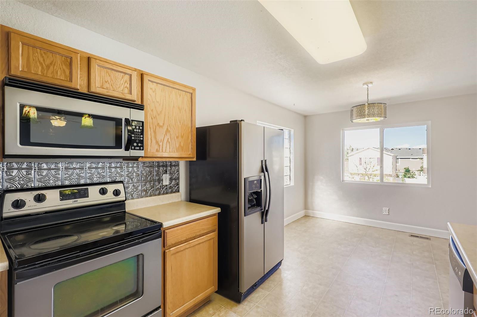 4716 Andes Street Denver, CO 80249 - Photo 14 of 27 a kitchen with a stove microwave and refrigerator