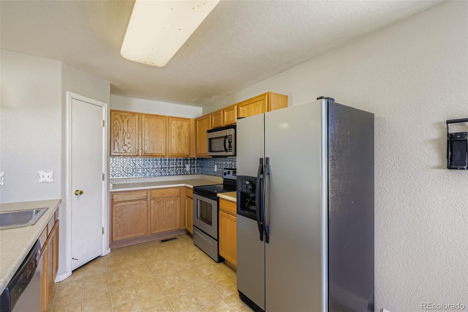 4716 Andes Street Denver, CO 80249 - Photo 15 of 27 a kitchen with stainless steel appliances granite countertop a refrigerator and a stove top oven