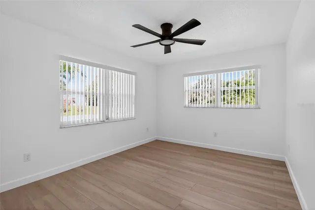 a view of empty room with wooden floor and fan