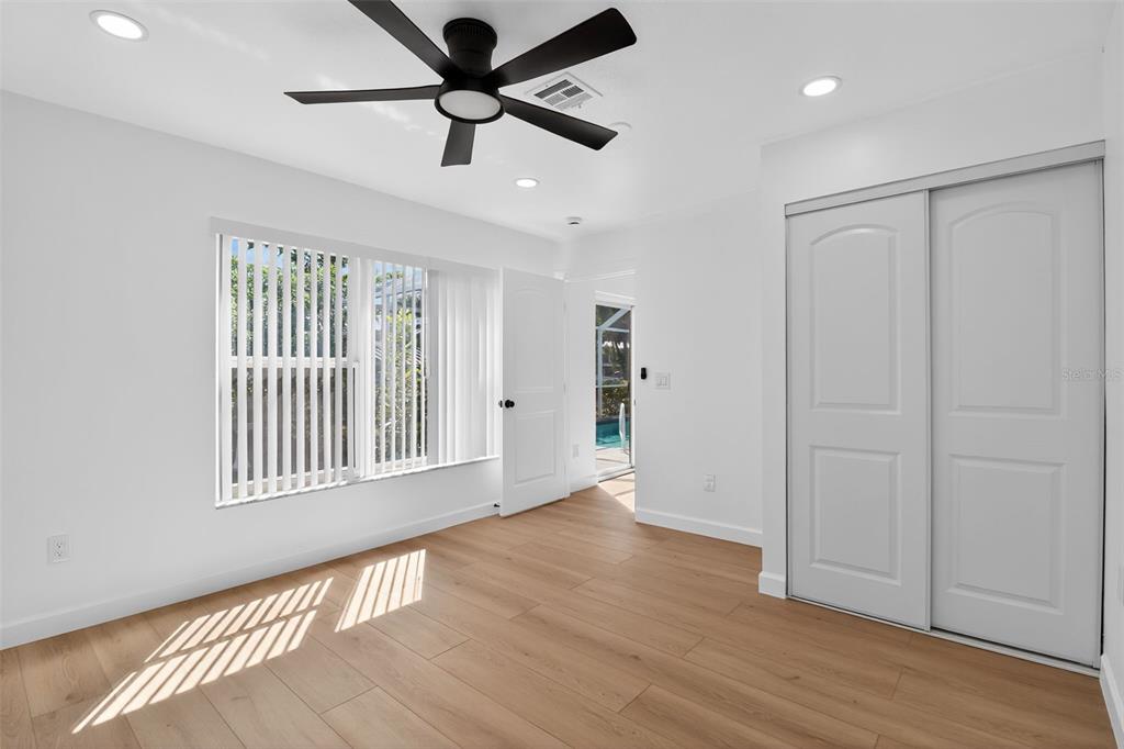 4210 Palm Drive Punta Gorda, FL 33950 - Photo 21 of 30 an empty room with wooden floor chandelier fan and windows