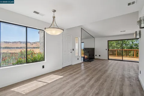 a view of a room with wooden floor fireplace and windows