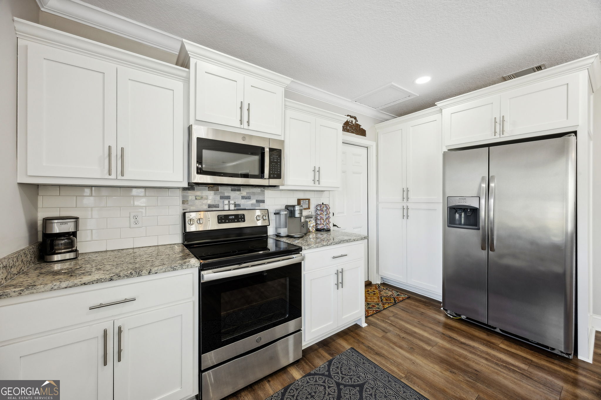 383 1st Street Folkston, GA 31537 - Photo 26 of 81 a kitchen with granite countertop a refrigerator stove and microwave