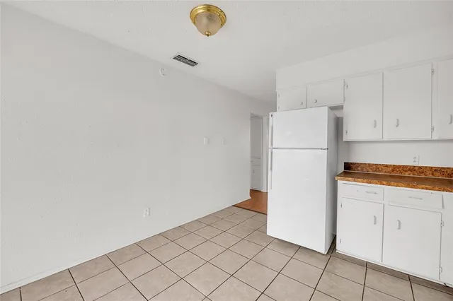 a view of a kitchen with refrigerator and white cabinets