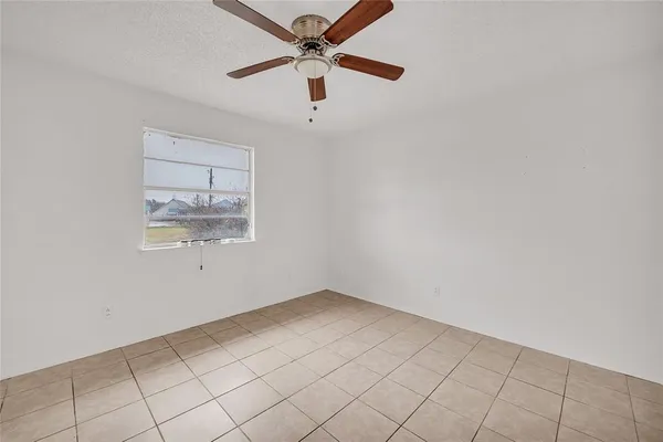 an empty room with a window and ceiling fan