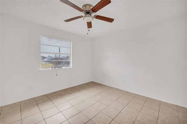 an empty room with a window and ceiling fan