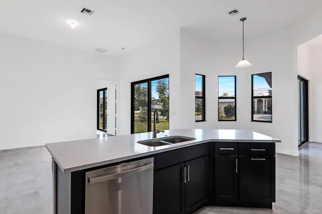 a kitchen with stainless steel appliances kitchen island granite countertop a refrigerator oven a sink with wooden cabinets and floors