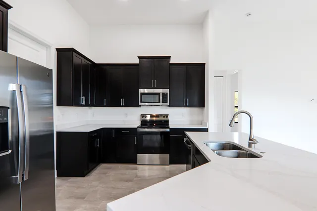 a kitchen with granite countertop a sink cabinets and stainless steel appliances