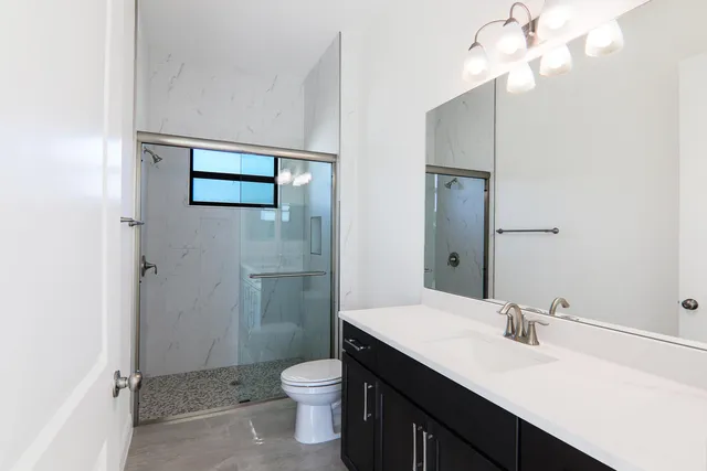 a bathroom with a granite countertop bathtub shower sink mirror vanity and toilet