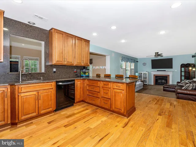 a large kitchen with stainless steel appliances granite countertop a stove a sink dishwasher a microwave oven with cabinets and wooden floor