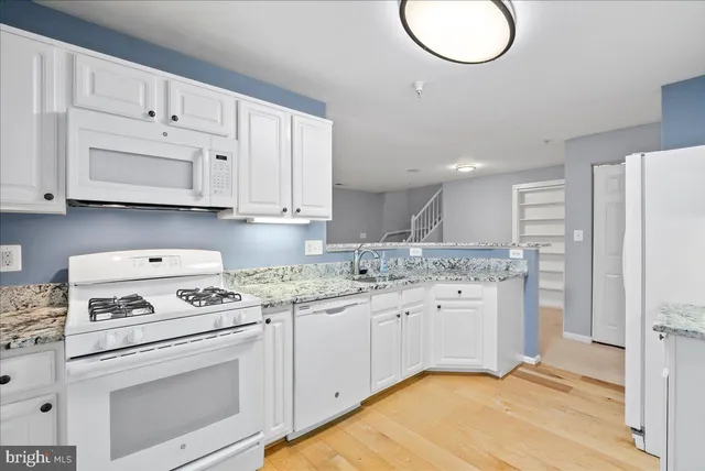 a kitchen with granite countertop a white stove sink and cabinets