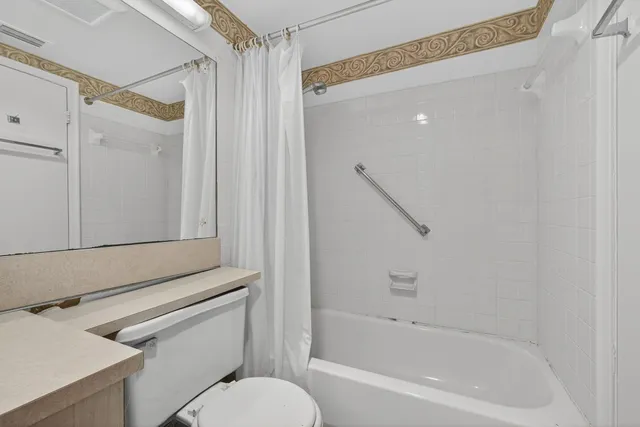 a bathroom with a granite countertop bathtub shower sink vanity and toilet