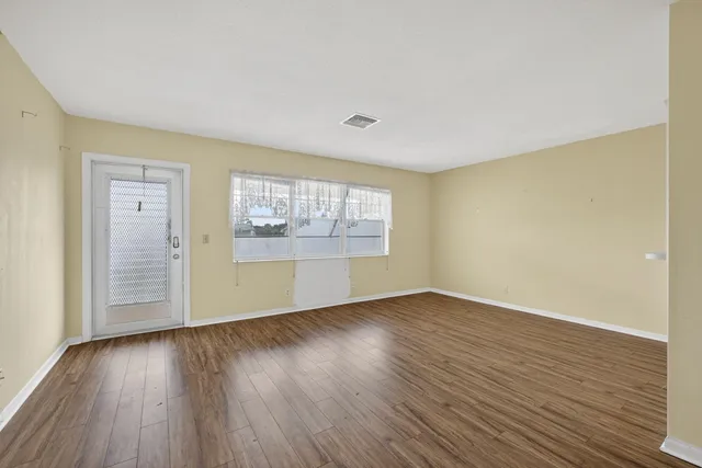 an empty room with wooden floor and windows