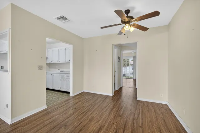 a view of empty room with wooden floor and ceiling fan