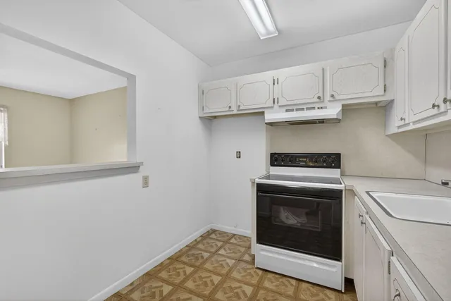 a kitchen with granite countertop white cabinets and white appliances