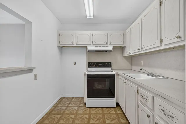 a kitchen with stainless steel appliances granite countertop a sink and dishwasher a stove top oven with white cabinets