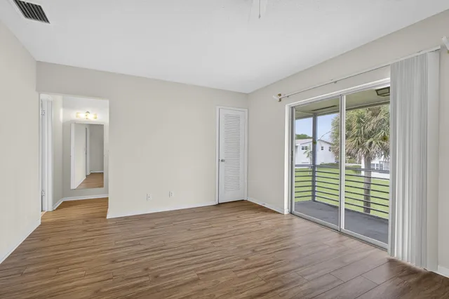 an empty room with wooden floor and windows