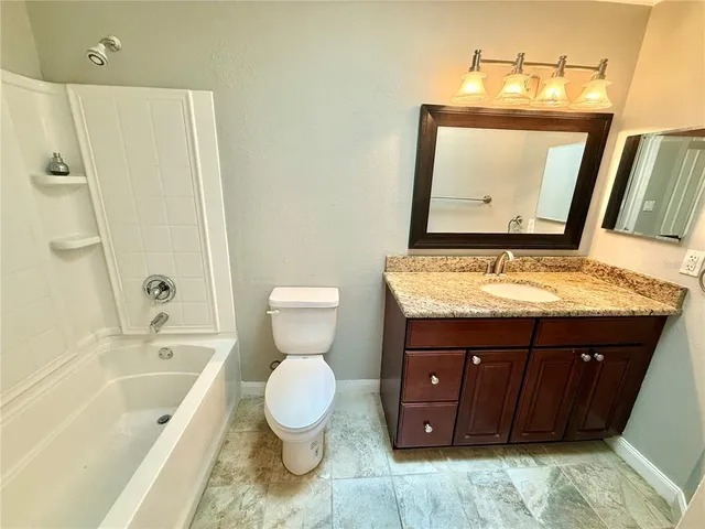 a bathroom with a granite countertop toilet sink and mirror