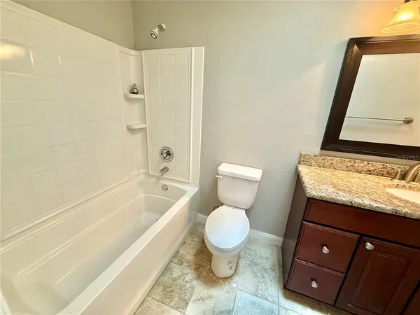 a bathroom with a granite countertop toilet sink and mirror