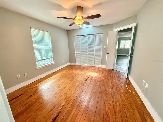 a view of an empty room with wooden floor and a window