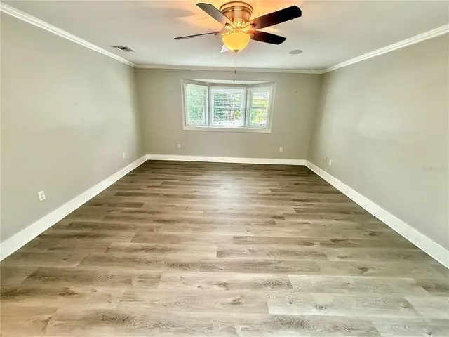 an empty room with wooden floor fan and windows