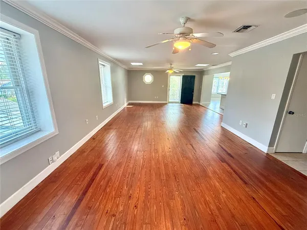 a view of an empty room with wooden floor and a window