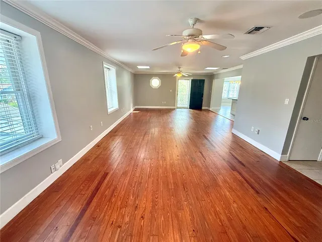 a view of an empty room with wooden floor and a window