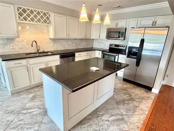 a kitchen with stainless steel appliances granite countertop a sink a stove a microwave a counter top space and cabinets