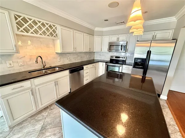 a kitchen with granite countertop a sink a counter top space appliances and cabinets