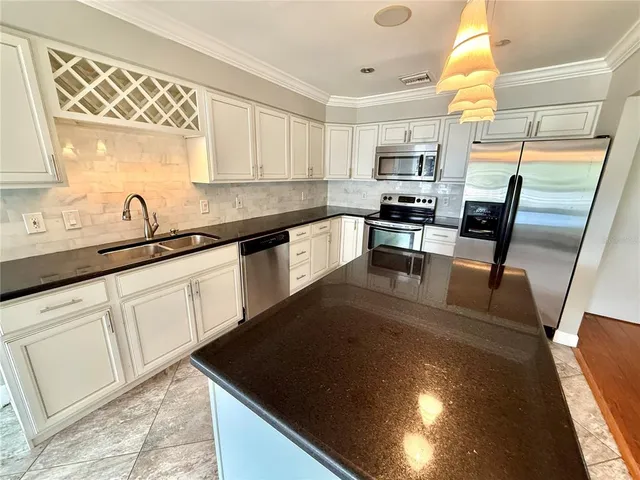 a kitchen with granite countertop a sink a counter top space appliances and cabinets