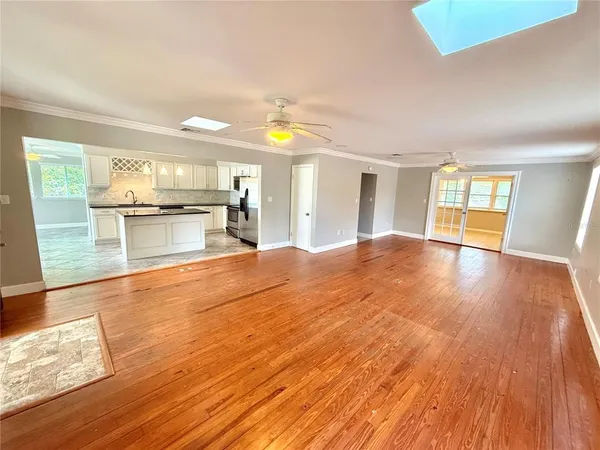 a open kitchen with a sink dishwasher stove and wooden floor next to a window