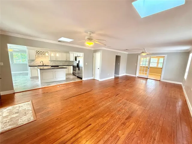 a open kitchen with a sink dishwasher stove and wooden floor next to a window