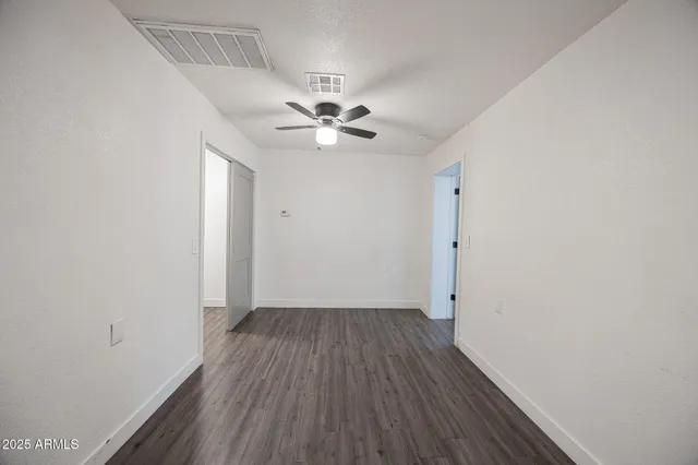an empty room with wooden floor and a ceiling fan