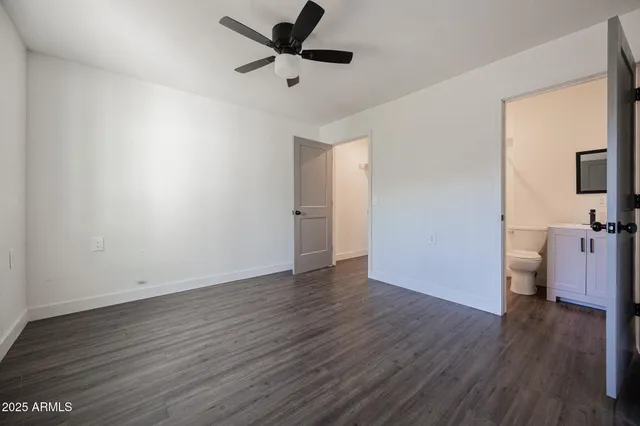 an empty room with wooden floor and a ceiling fan