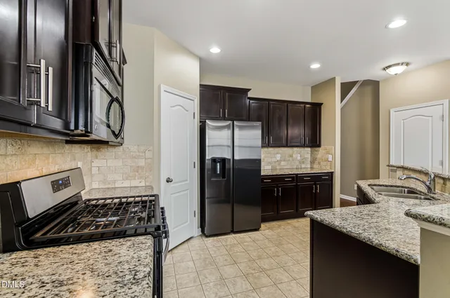 a kitchen with granite countertop kitchen island stainless steel appliances a refrigerator stove top oven and sink