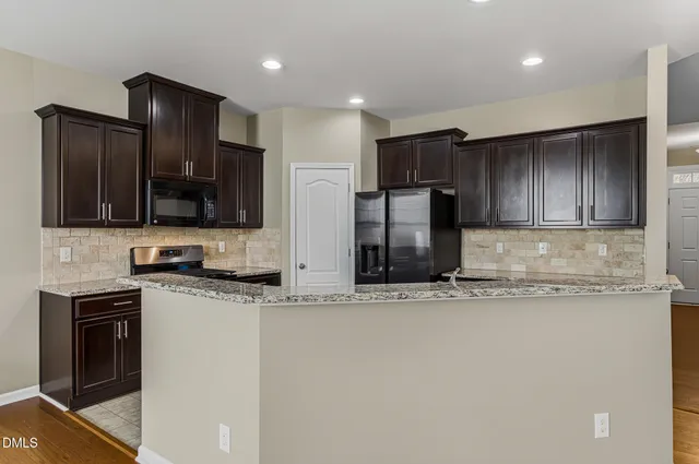 a kitchen with stainless steel appliances granite countertop a sink a stove a refrigerator and a microwave