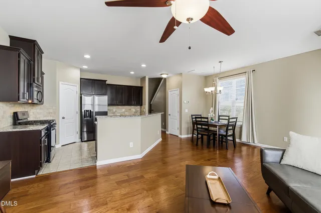 a living room with stainless steel appliances furniture a dining table and kitchen view