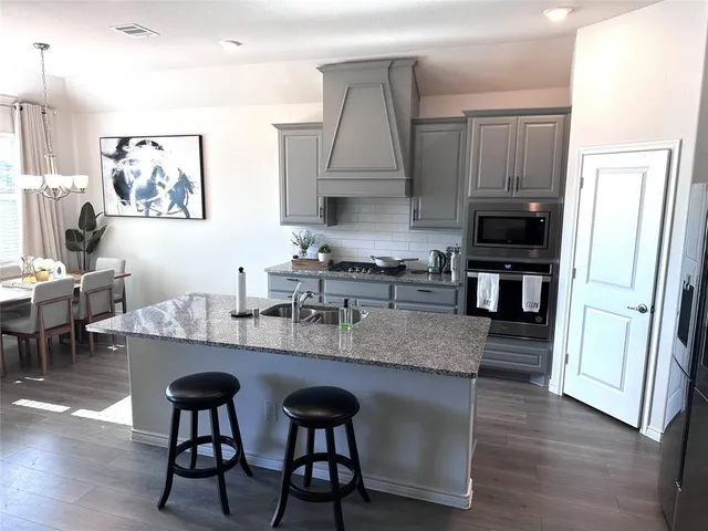 a kitchen with stainless steel appliances granite countertop a table chairs microwave and sink