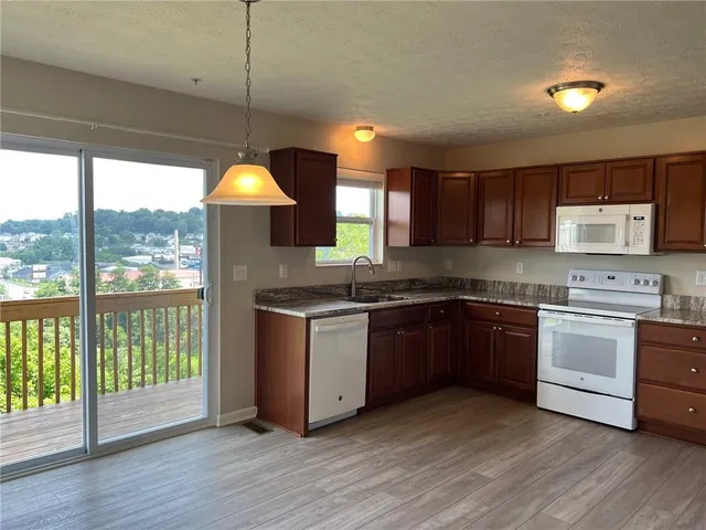 a kitchen with granite countertop wooden floors a stove a sink and a window